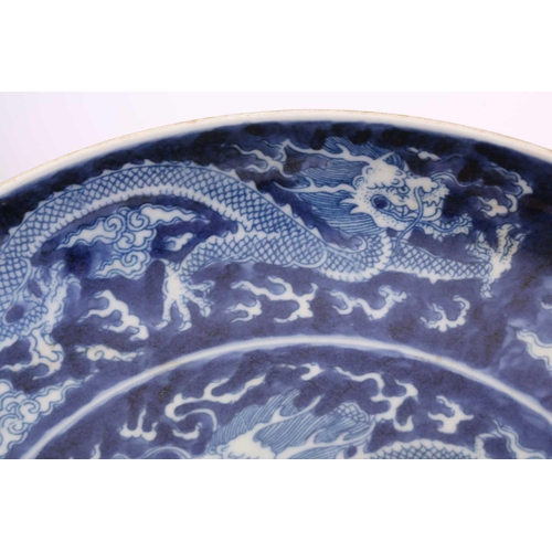 220 - A Chinese porcel;ain blue & white dragon dish, painted with a central dragon bordered by two further... 