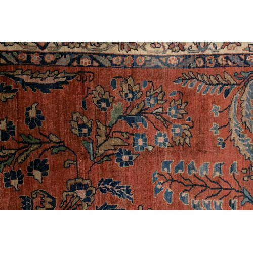 321 - An old silk Kashan rug with stylized shrubs and flowers on a dark brick red ground, within meanderin... 