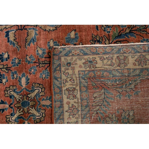 321 - An old silk Kashan rug with stylized shrubs and flowers on a dark brick red ground, within meanderin... 