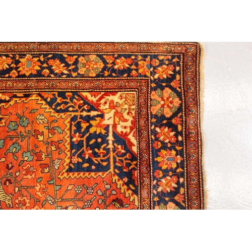 326 - An old Tabriz rug with a central star motif with hanging lanterns and animals and shrubs on crimson ... 