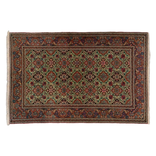 329 - An old Kirman/ Kerman rug with allover floral tiled pattern on a pistachio green ground, within an A... 