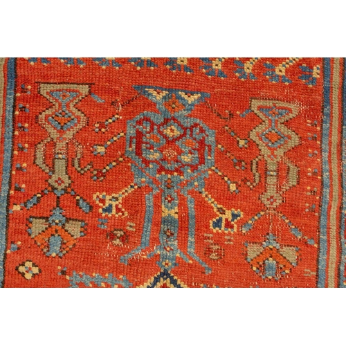 331 - An old Turkish Ushak rug with a stylized tree of life design on a tomato red ground within multiple ... 