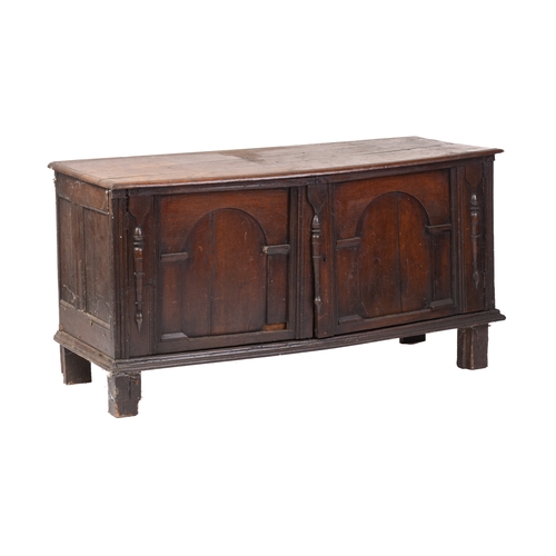 263A - An 18th century and later oak low cupboard with a planked top above a pair of arch-panelled doors wi... 