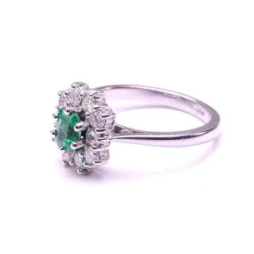 11 - An emerald and diamond entourage ring in 18ct white gold, featuring an emerald-cut emerald of 4.9 x ... 