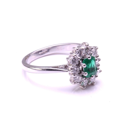 11 - An emerald and diamond entourage ring in 18ct white gold, featuring an emerald-cut emerald of 4.9 x ... 