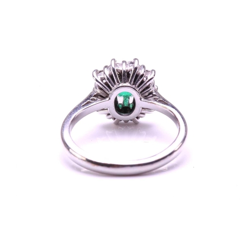 11 - An emerald and diamond entourage ring in 18ct white gold, featuring an emerald-cut emerald of 4.9 x ... 