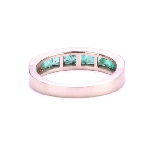 118 - An emerald half eternity ring, with seven square-shaped step-cut emeralds in channel setting, to a t... 