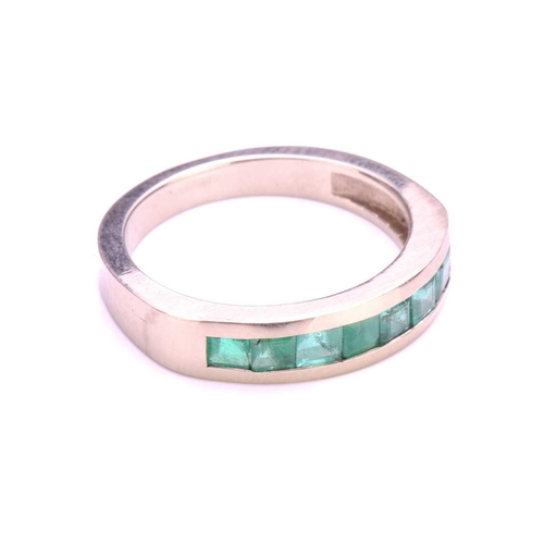 118 - An emerald half eternity ring, with seven square-shaped step-cut emeralds in channel setting, to a t... 