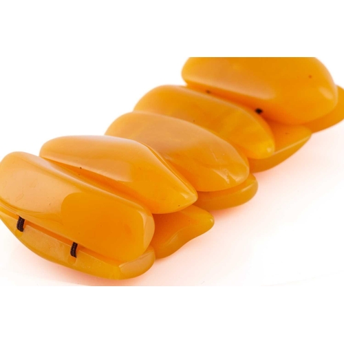 119 - An egg yolk amber panel bracelet; of ten shaped oval and rectangular panels. 100 grams