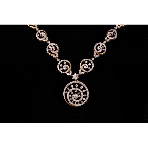 12 - A diamond-set necklace and earrings suite, of swirl designs; the necklace comprises a circular motif... 