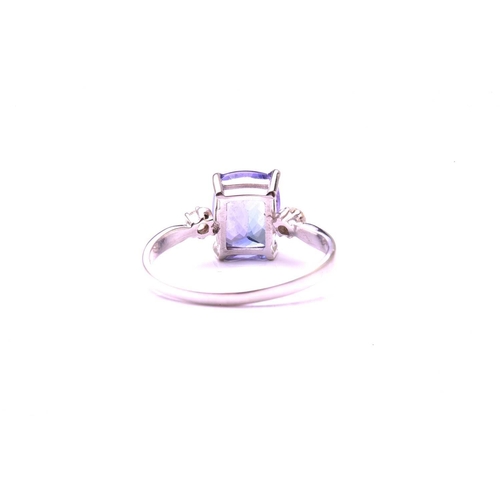 130 - A single stone tanzanite ring with diamond set shoulders; the oval cut tanzanite in four claw mount ... 