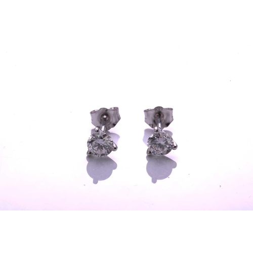 139 - A pair of diamond earrings, each comprising a round brilliant cut diamond in a three-claw setting, a... 