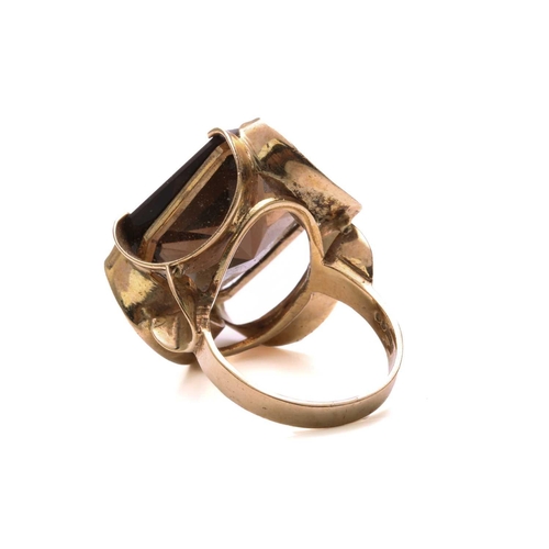 147 - A smoky quartz dress ring in 9ct yellow gold, composed of an octagonal modified scissors-cut smoky q... 