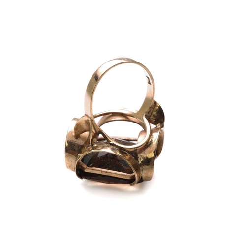 147 - A smoky quartz dress ring in 9ct yellow gold, composed of an octagonal modified scissors-cut smoky q... 