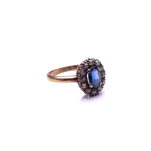 183 - A sapphire and diamond cluster ring; the oval cut sapphire claw mounted within a border of mixed old... 