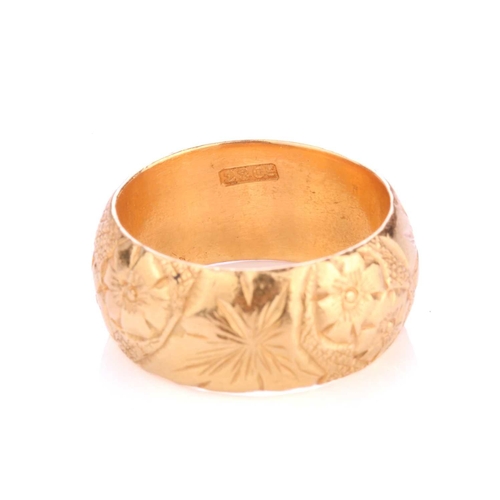 225 - A 22ct yellow gold ring, the thick D-section band has been engraved with floral designs throughout, ... 