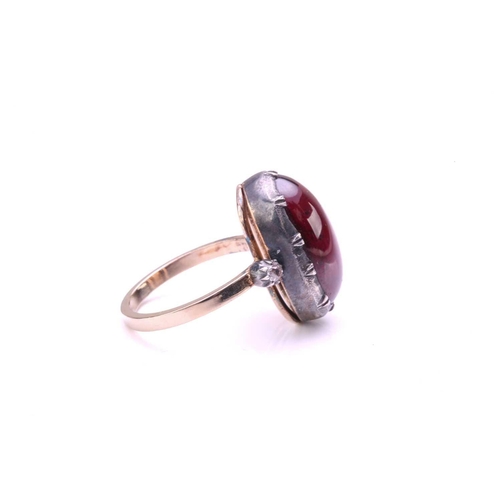 232 - A foil-backed garnet and diamond dress ring, contains a long oval garnet cabochon in scalloped colle... 