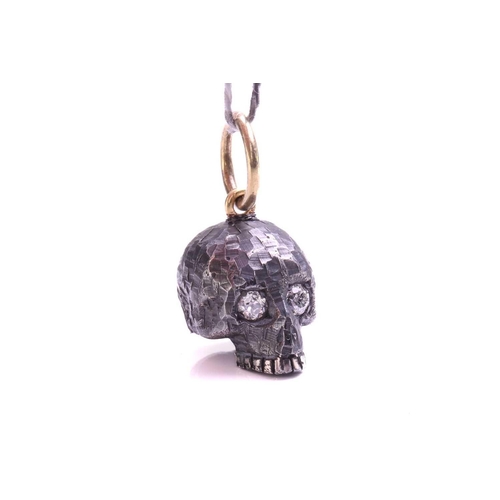 244 - A skull charm pendant with diamonds, a sculpted hollow skull with eyes set with old-cut diamonds, wi... 