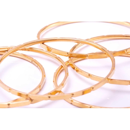 256 - A suite of six yellow metal bangles, with a faceted design, yellow metal unmarked (tests 18ct gold o... 