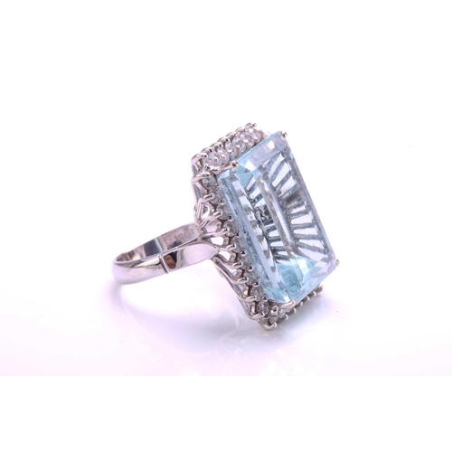 292 - A large aquamarine and diamond cluster ring, featuring a rectangular step-cut aquamarine with pale b... 