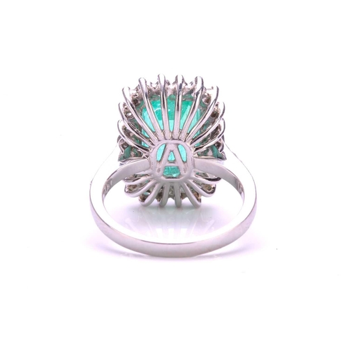 299 - An emerald and diamond halo ring in platinum, featuring a rectangular emerald-cut emerald with brigh... 