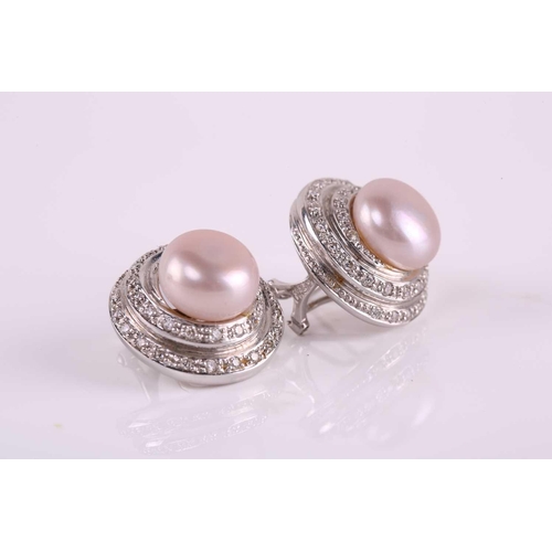 43 - A pair of pearl and diamond earrings; each comprises a round button-shaped silver pearl with pink ov... 