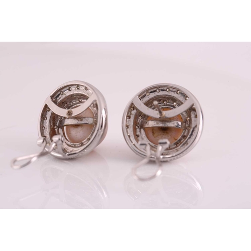 43 - A pair of pearl and diamond earrings; each comprises a round button-shaped silver pearl with pink ov... 