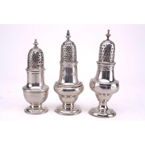 455 - Three George III silver sugar casters each with a spool knop and of baluster form with flared foot, ... 