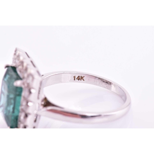 46 - An emerald and diamond halo ring, consisting of a central emerald approximately measuring 10.9 x 8.7... 