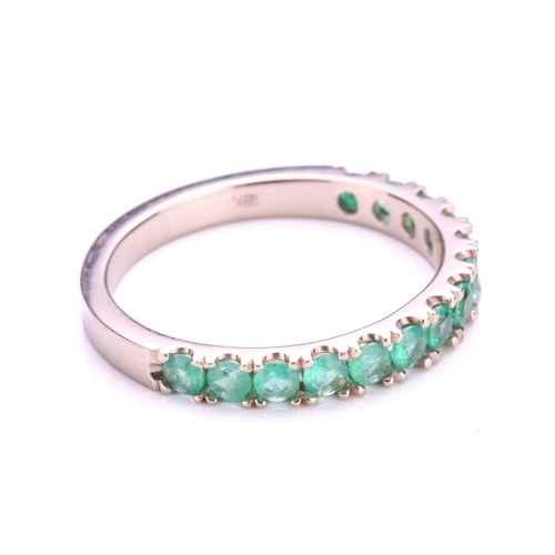 67 - An emerald half eternity ring, consisting of fourteen circular-cut emeralds in U-cut pavé settings, ... 