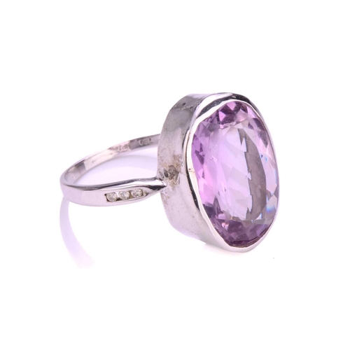 73 - An amethyst dress ring in 18ct white gold, comprising an oval-cut amethyst in tube collet, approxima... 