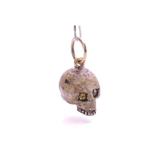 8 - An enamel skull charm pendant, textured and mottled enamel on a sculpted hollow skull, eyes set with... 