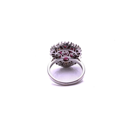 93 - A ruby and diamond cluster ring; the principal round brilliant cut diamond in a raised claw mount ab... 