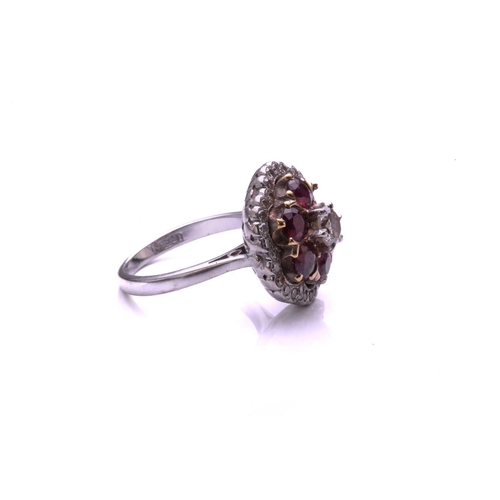 93 - A ruby and diamond cluster ring; the principal round brilliant cut diamond in a raised claw mount ab... 