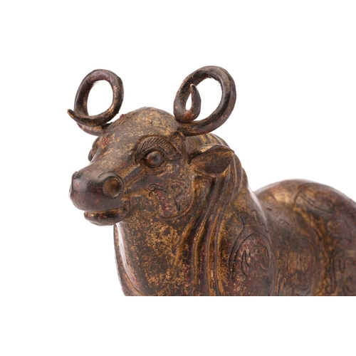 203 - A Chinese patinated and gilt bronze figure of an Oxen with curled horns and a body engraved with fla... 