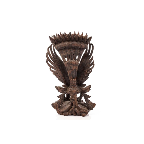 222 - A Balinese-carved and pierced hardwood figure of Vishnu riding on his mount; the winged Garuda, who ... 