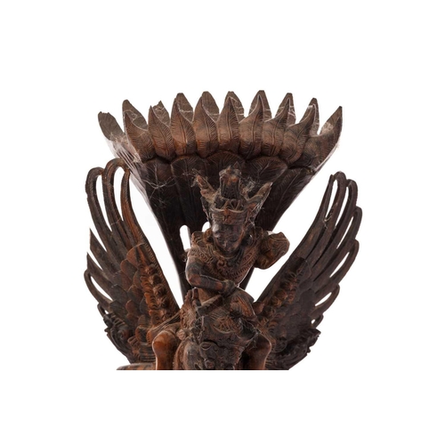 222 - A Balinese-carved and pierced hardwood figure of Vishnu riding on his mount; the winged Garuda, who ... 