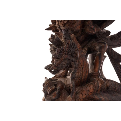 222 - A Balinese-carved and pierced hardwood figure of Vishnu riding on his mount; the winged Garuda, who ... 