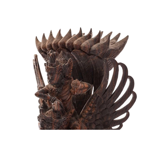 222 - A Balinese-carved and pierced hardwood figure of Vishnu riding on his mount; the winged Garuda, who ... 