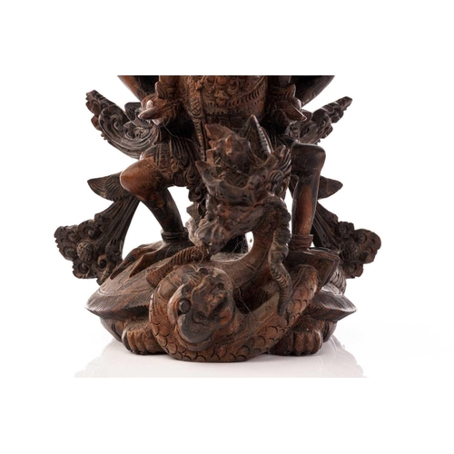 222 - A Balinese-carved and pierced hardwood figure of Vishnu riding on his mount; the winged Garuda, who ... 