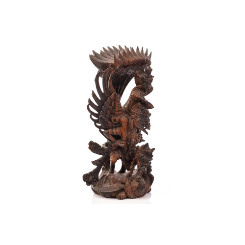 222 - A Balinese-carved and pierced hardwood figure of Vishnu riding on his mount; the winged Garuda, who ... 