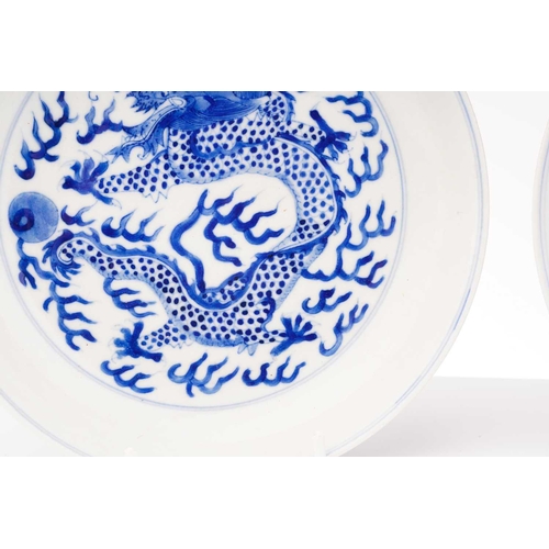 234 - A pair of Chinese porcelain blue & white 'Dragon' dishes, painted with a writhing dragon chasing a p... 