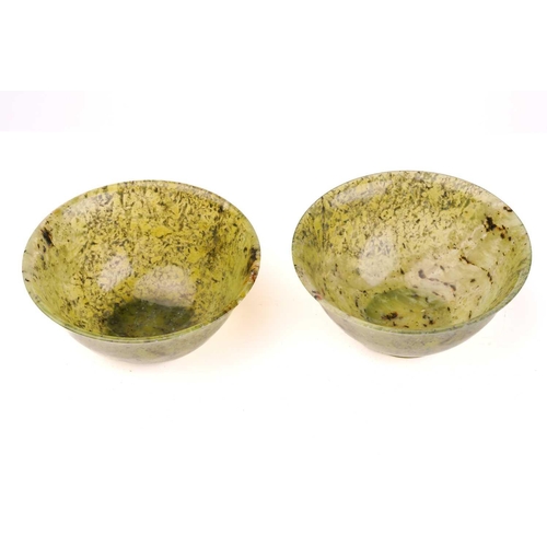 241 - A pair of Eastern circular variegated moss green jade bowls with slightly everted rims each on turne... 