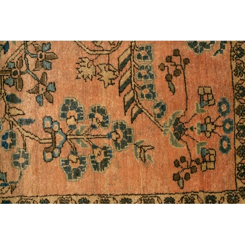 307 - An old Sarouk rug with floral sprays on a typical dusky pink ground within a meandering indigo groun... 