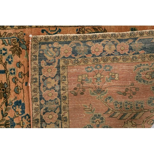 307 - An old Sarouk rug with floral sprays on a typical dusky pink ground within a meandering indigo groun... 