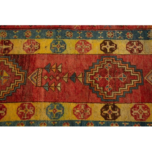 312 - A lacquer red ground probably Luri Gabbeh runner with four stepped diamond design within geometric b... 