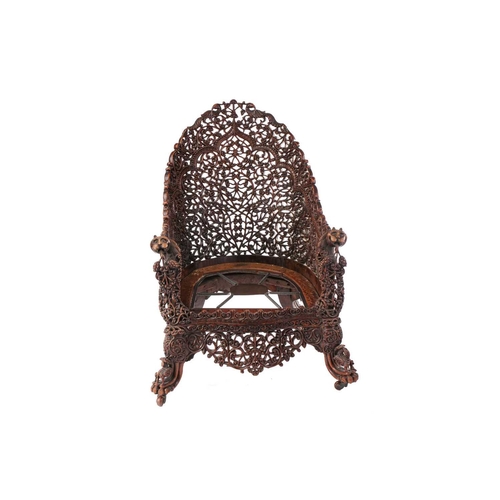 332 - A 19th century Anglo Indian carved and pierced paduak wood high back tub chair, the arched back prof... 