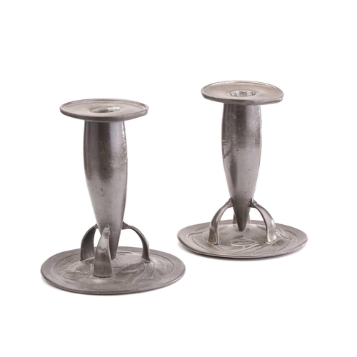 354 - Liberty & Co, a pair of Tudric pewter candlesticks, the bullet shape stems with three supports on sc... 