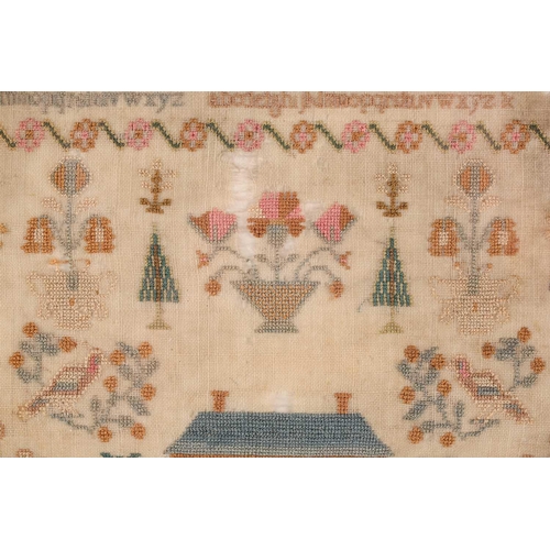 356 - A George III woolwork sampler, with the alphabet over a house surrounded by trees and pots of plants... 