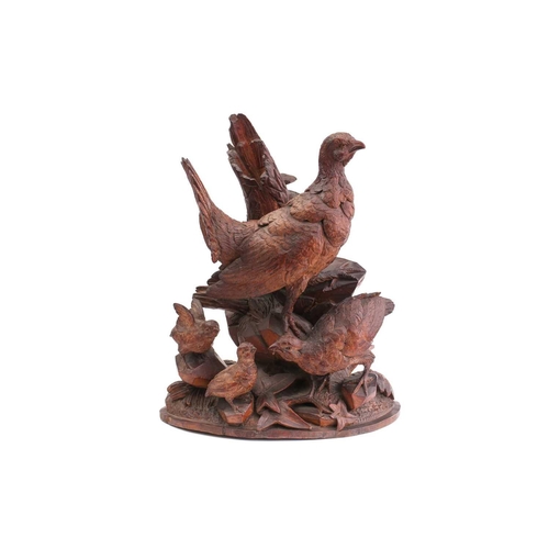 357 - A pair of Black Forest carved wood figures of partridges, with their offspring, on ivy-carved natura... 